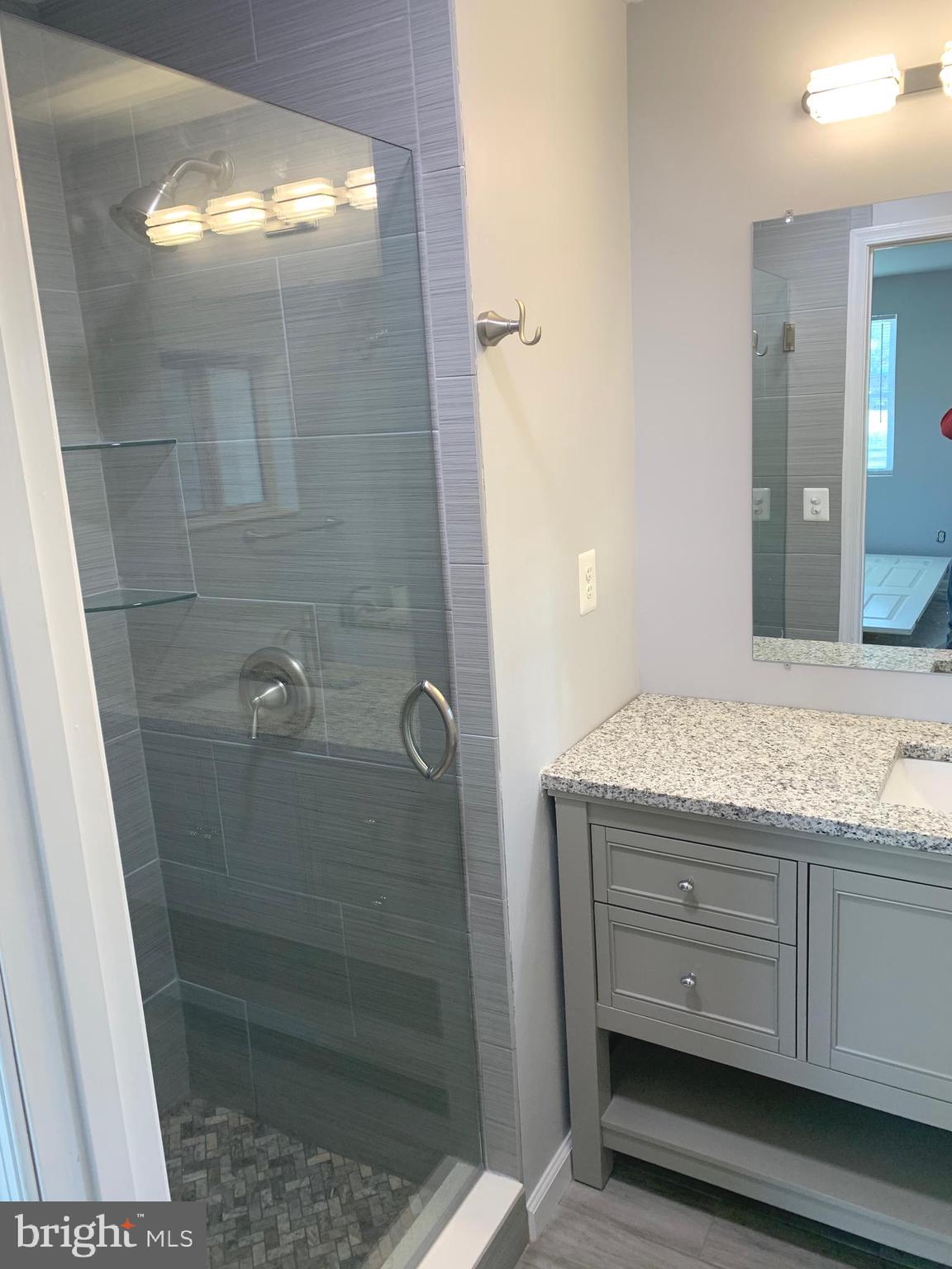 7703 Dover Road Glen Burnie, MD 21060 - Photo 16 of 25 a bathroom with a granite countertop sink a shower and a mirror