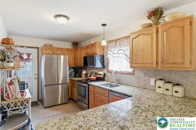 a kitchen with stainless steel appliances granite countertop a refrigerator a sink dishwasher a stove with wooden cabinets