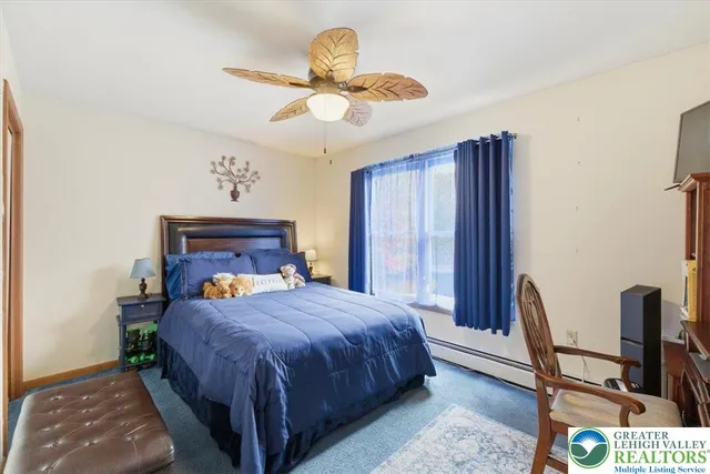 a bedroom with a bed a chair and potted plant on the dresser