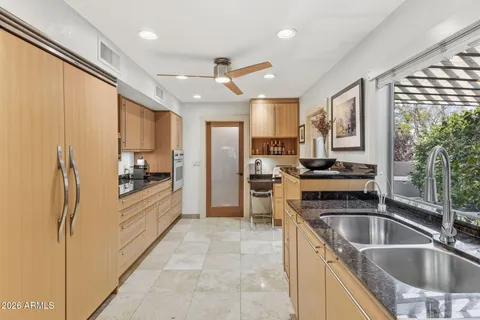a kitchen with stainless steel appliances a sink a stove a refrigerator cabinets and furniture