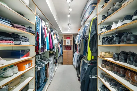a view of walk in closet with clothes and shoes