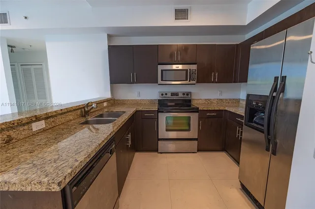 a bathroom with a granite countertop toilet a sink a mirror and a window