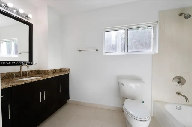 a bathroom with a granite countertop toilet a sink and a mirror