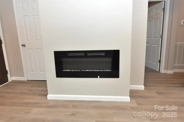 an empty room with wooden floor chandelier fan and window