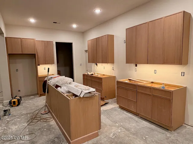 a room with kitchen island a sink stainless steel appliances and cabinets