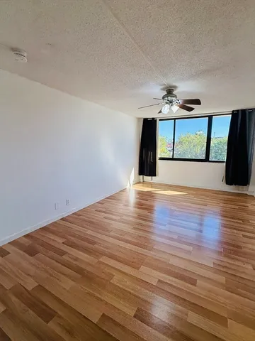 a view of an empty room with window and wooden floor