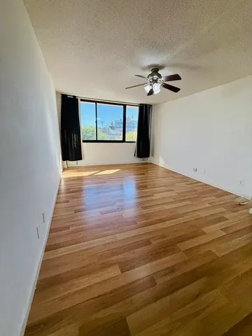 a view of an empty room with window and wooden floor