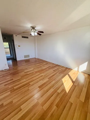 a view of a room with wooden floor and a ceiling fan