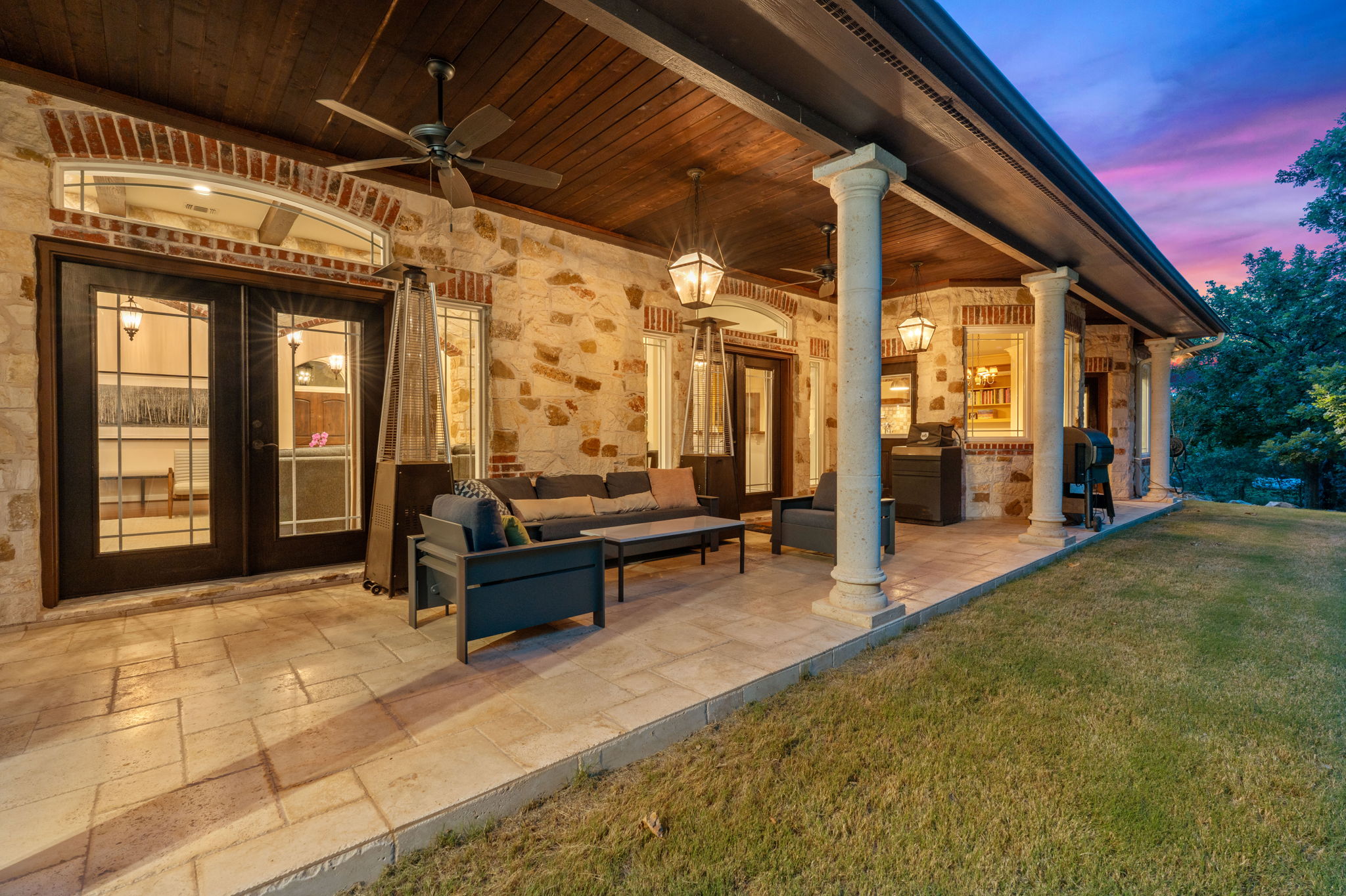 8121 Bluff Trail Austin, TX 78737 - Photo 32 of 40 An inviting covered patio featuring ample seating, elegant columns, and outdoor lighting, perfect for evening gatherings.