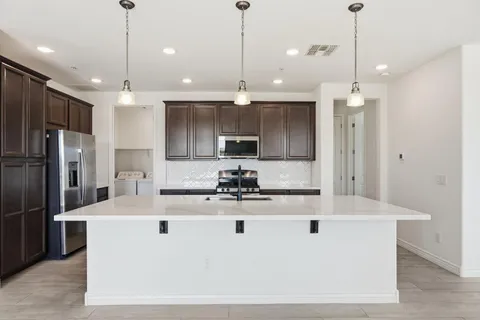 a kitchen with kitchen island a counter top stainless steel appliances and a chandelier