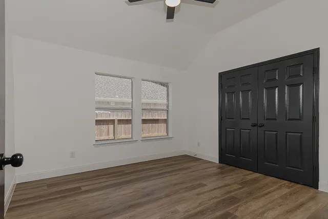 an empty room with wooden floor cabinet and windows