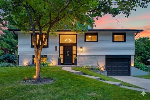 a front view of a house with a yard and tree