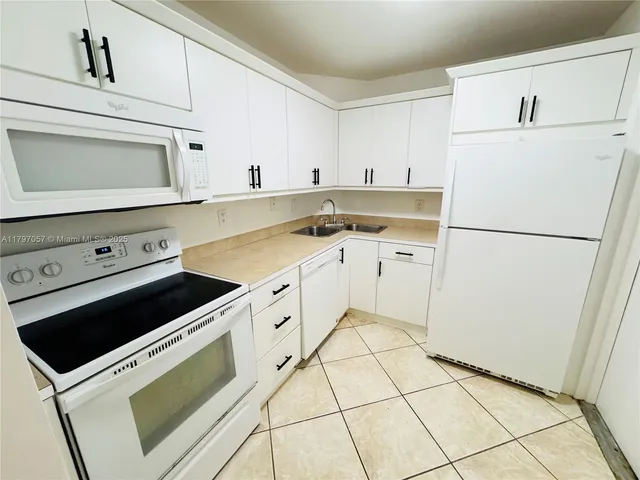 a kitchen with white cabinets and white appliances