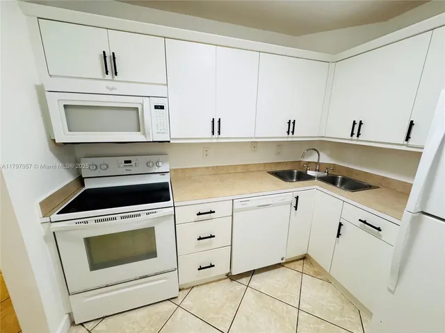 a kitchen with white cabinets appliances and a sink