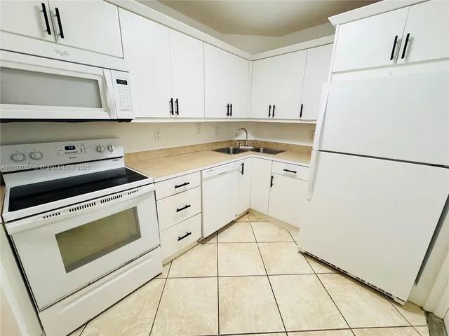 a kitchen with white cabinets and white appliances