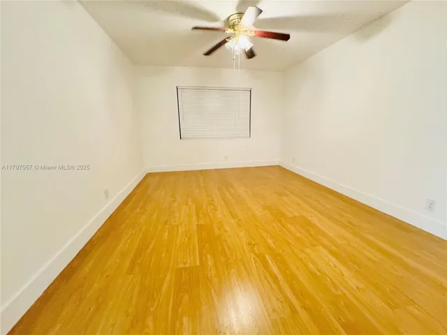 a view of a room with wooden floor and ceiling fan