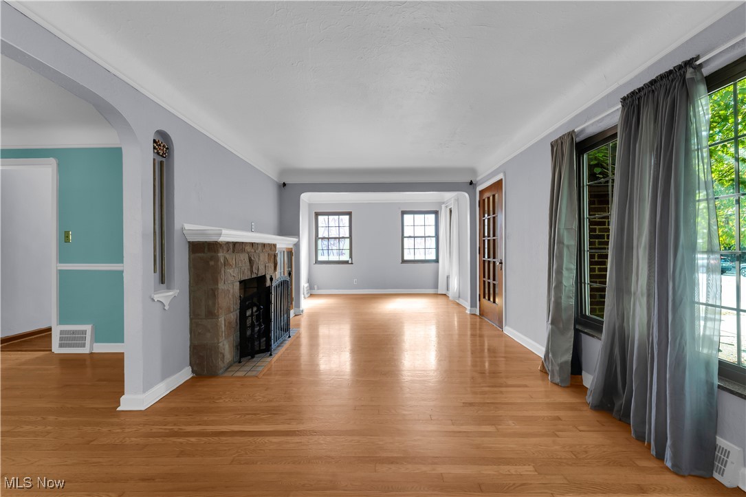 3739 Warren Road Cleveland, OH 44111 - Photo 33 of 40 Unfurnished living room featuring light wood-style flooring, arched walkways, a fireplace, and ornamental molding