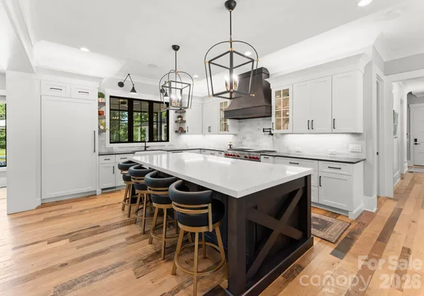 a kitchen with stainless steel appliances kitchen island granite countertop a table chairs in it and wooden floors