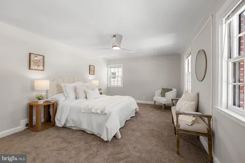 a spacious bedroom with a bed a mirror on dresser and a chandelier