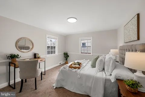 a bedroom with a bed a couch and a lamp on dresser