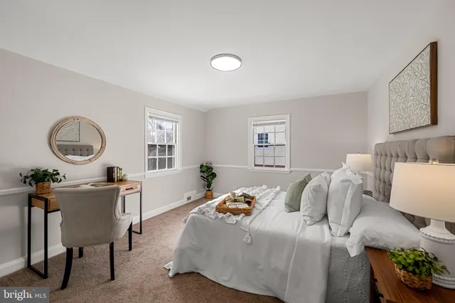 a bedroom with a bed a couch and a lamp on dresser