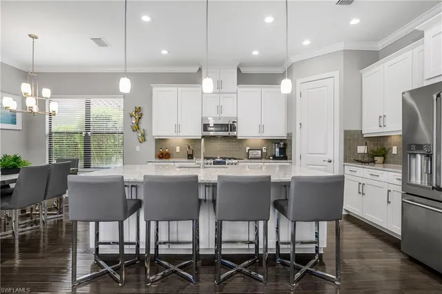 a kitchen with stainless steel appliances granite countertop a table chairs sink refrigerator and cabinets
