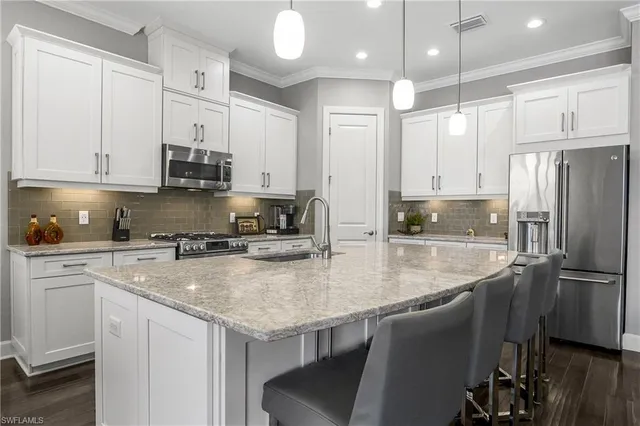 a kitchen with stainless steel appliances granite countertop a refrigerator a sink and white cabinets