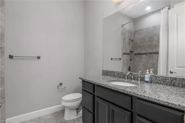 a bathroom with a granite countertop sink a toilet and a mirror