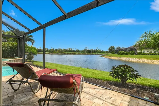 a view of a lake with table and chairs under an umbrella