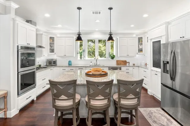 a kitchen with a refrigerator a stove a sink and chairs