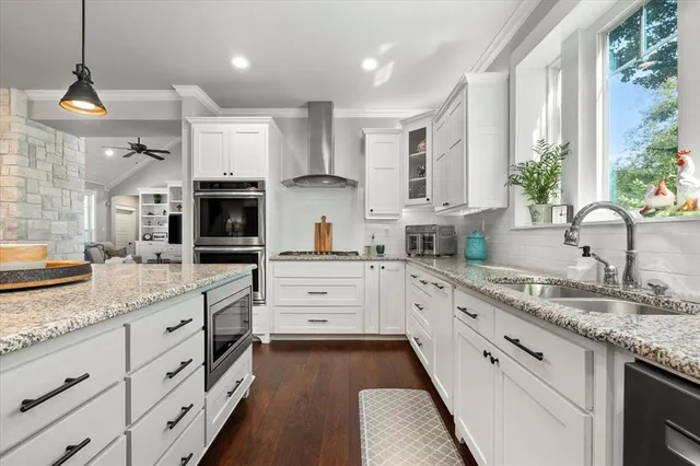 a kitchen with granite countertop a sink stainless steel appliances and white cabinets