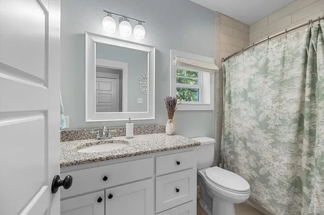 a bathroom with a granite countertop sink toilet and a mirror
