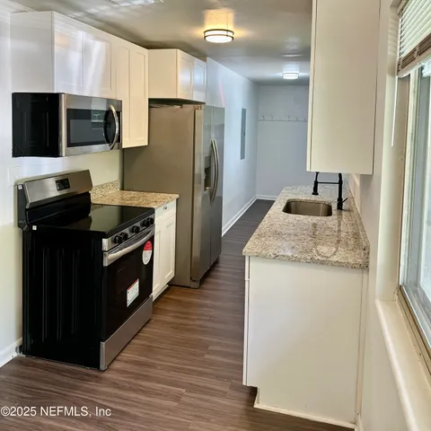 a kitchen with granite countertop a refrigerator and a stove top oven