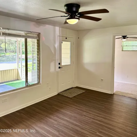 an empty room with wooden floor fan and windows