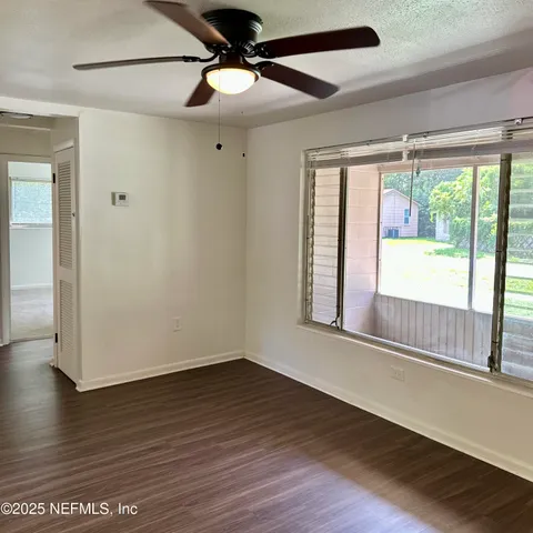 a view of an empty room with wooden floor and a window