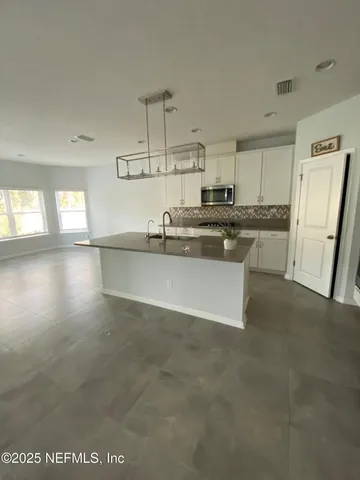 a kitchen with stainless steel appliances granite countertop a sink a stove a refrigerator and white cabinets