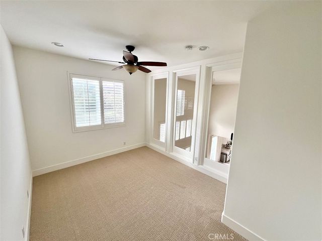 an empty room with windows and chandelier fan