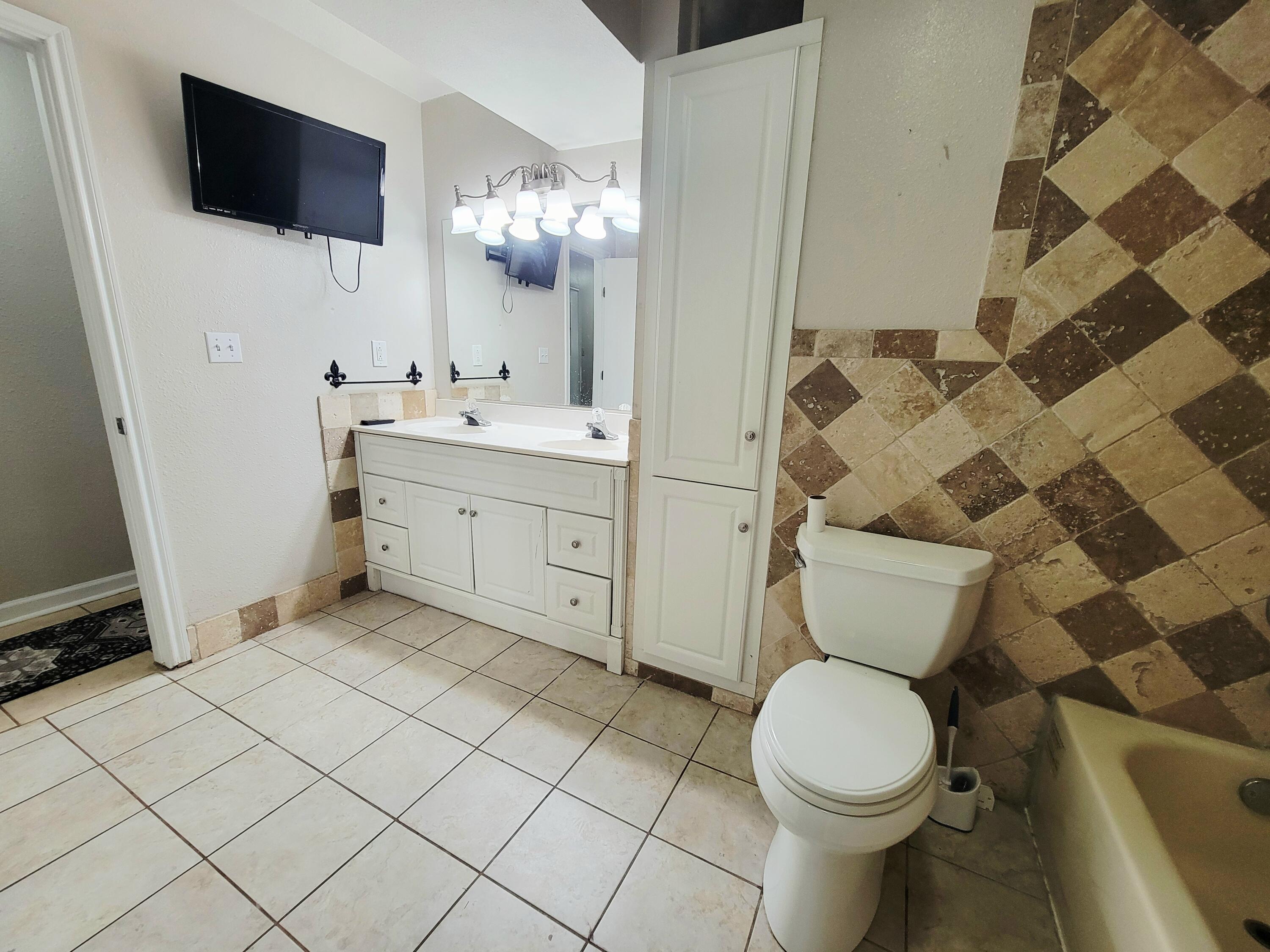 3408 38th Street Lubbock, TX 79413 - Photo 13 of 18 a bathroom with a toilet a sink and a mirror