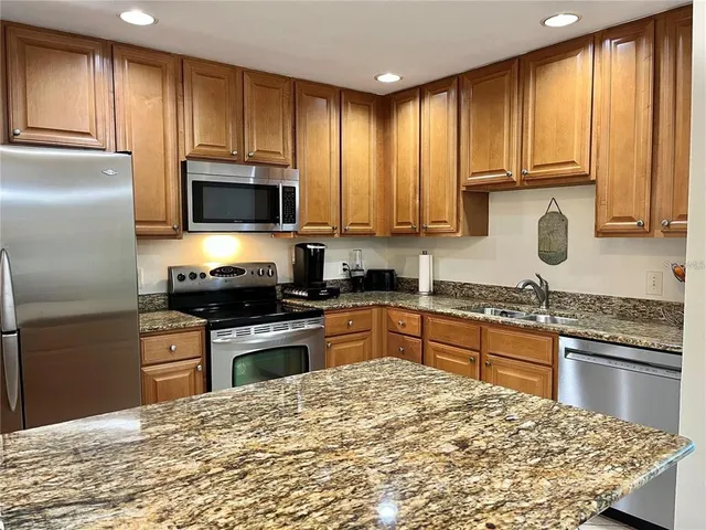 a kitchen with granite countertop wooden cabinets stainless steel appliances and a window