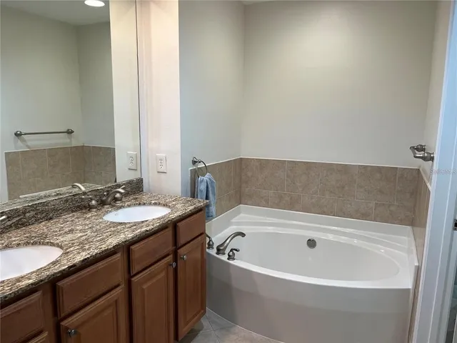 a bathroom with a granite countertop sink and a bathtub