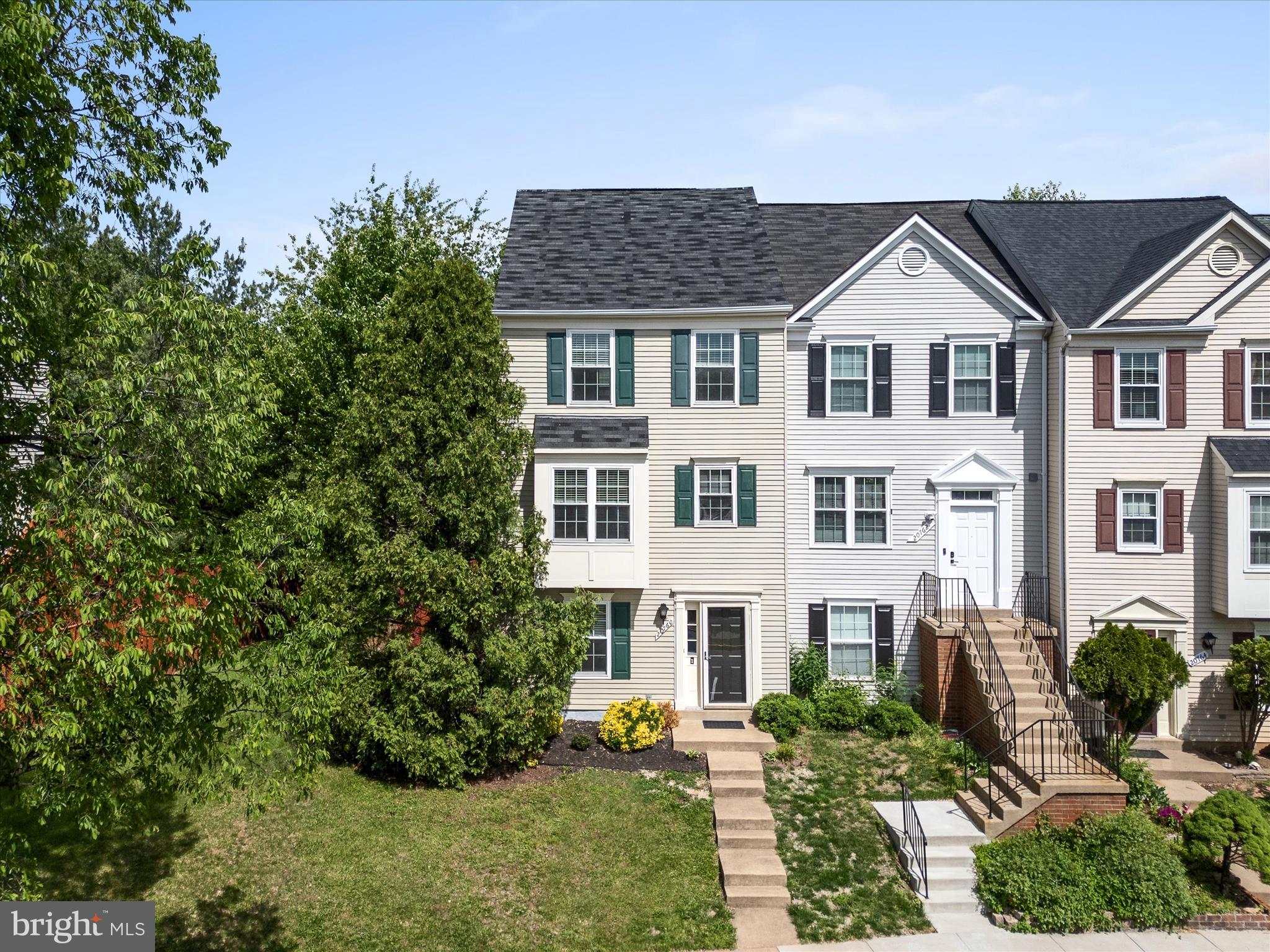 20760 Apollo Terrace Ashburn, VA 20147 - Photo 2 of 50 a view of a white house with large windows and a yard with plants and large trees