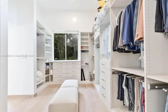 a view of walk in closet with clothes and shoes