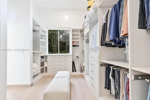 a view of walk in closet with clothes and shoes