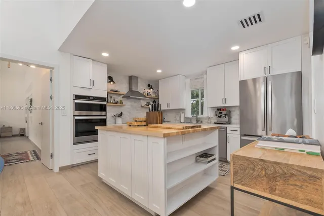 a kitchen with stainless steel appliances granite countertop a refrigerator and a stove top oven