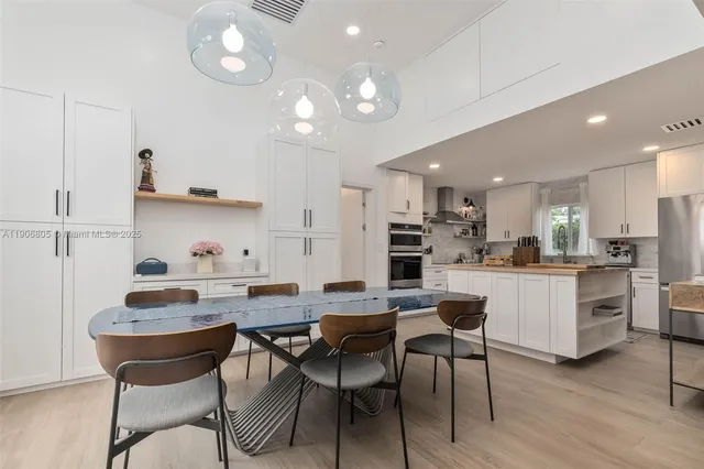 a kitchen with a dining table chairs stainless steel appliances and cabinets