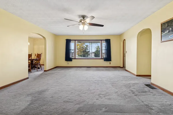 an empty room with windows and chandelier fan