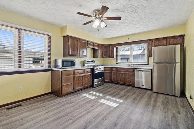 a kitchen with wooden floors and white stainless steel appliances