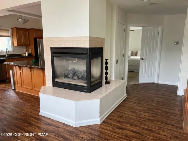 a living room with stainless steel appliances wooden floor and a fireplace