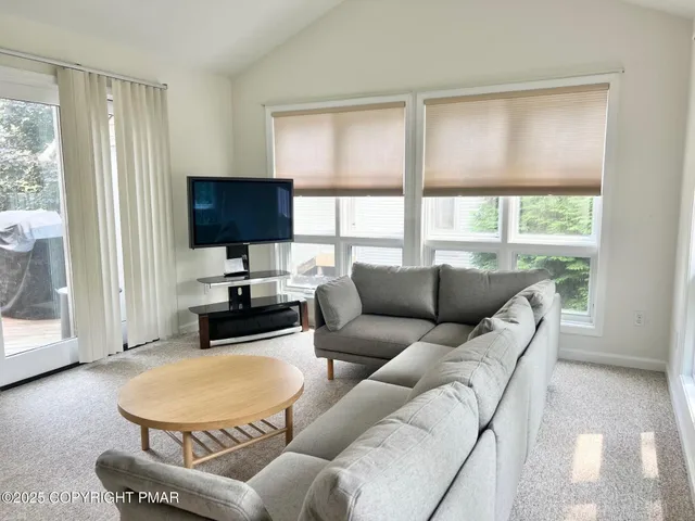 a living room with furniture a large window and a flat screen tv