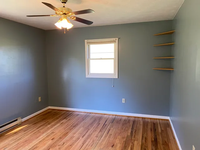 an empty room with a window and wooden floor